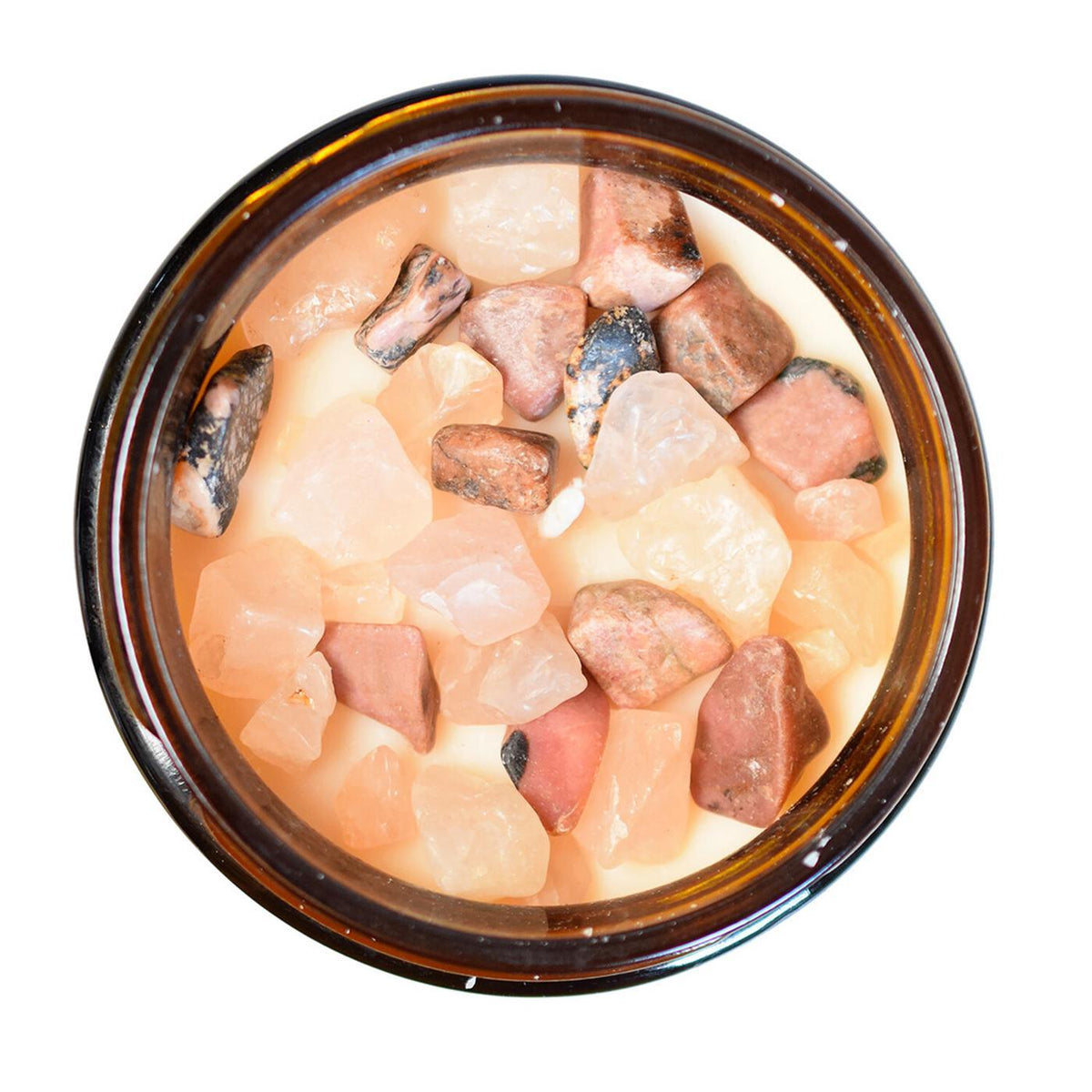 Vue du dessus d'un pot de bougie en verre ambré révélant une multitude de pierres naturelles brutes de quartz rose et de rhodonite incrustées dans la cire