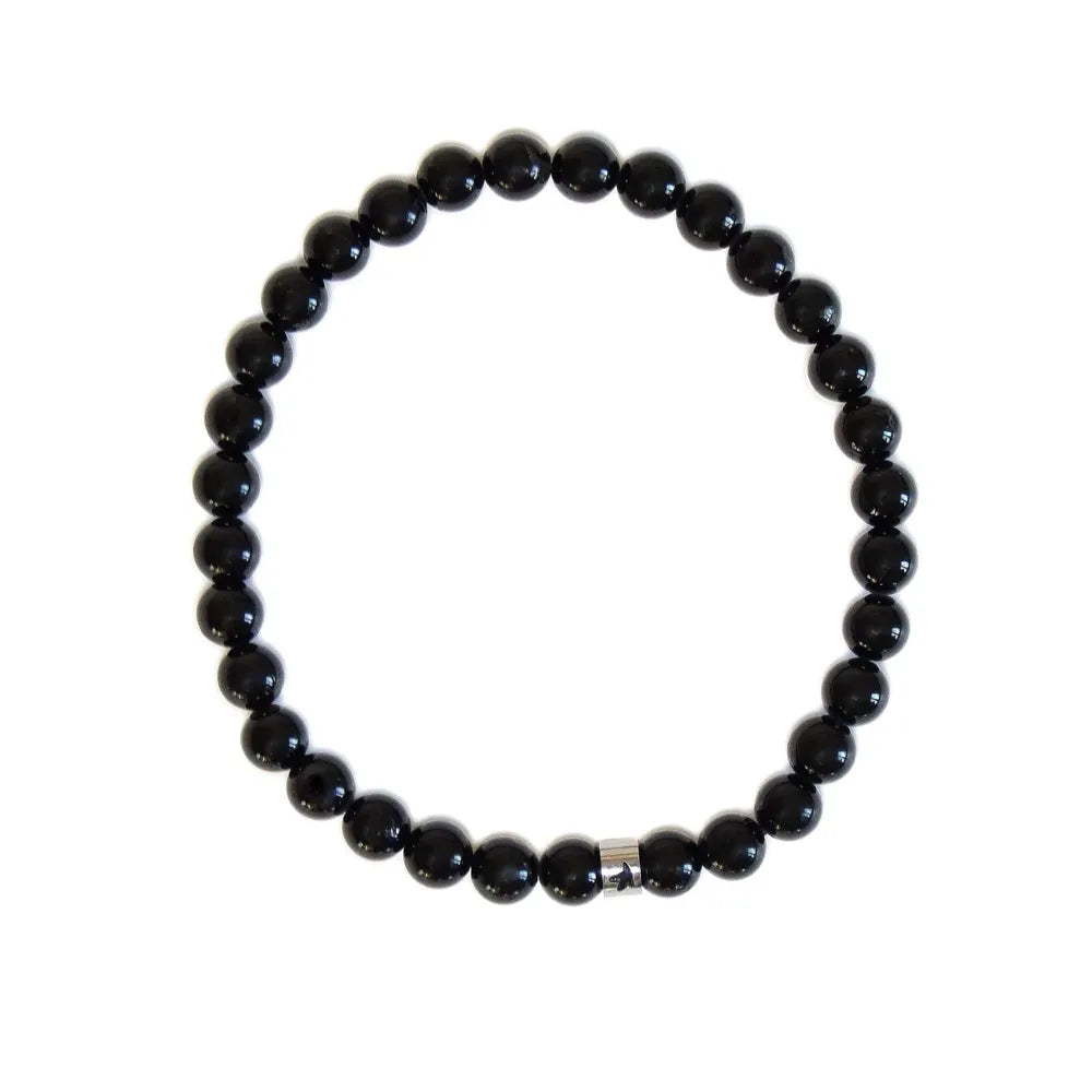 Vue de dessus d'un bracelet élastique en perles rondes de tourmaline noire avec une perle séparatrice en acier inoxydable gravée Omsaé, présenté à plat sur un fond blanc.