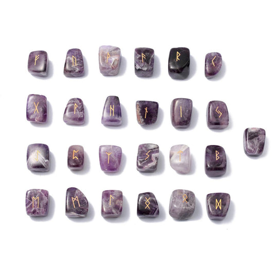 Les 24 runes en améthyste violette gravées de doré soigneusement alignées en quatre rangées avec la rune vierge posée à droite, présentées à plat sur un fond blanc.